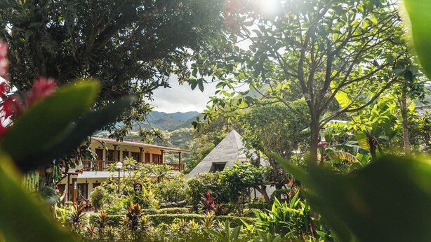 A hotel with a garden, a mountain view, and a triangular building. - Hostería Paraíso (Vilcabamba)