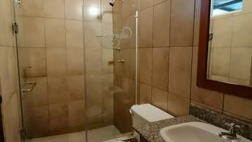 A bathroom with a shower, toilet, sink, and a mirror.