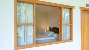 A bedroom with a bed, a nightstand, and a window with curtains.