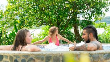 Una piscina de piedra con tres personas relajándose.