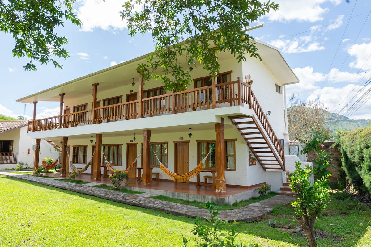 A two-story house with a balcony, wooden railings, and a staircase leading to the upper floor.
