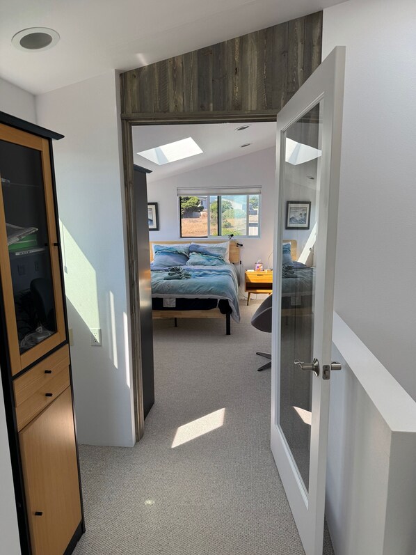 A bedroom with a bed, a bedside table, a wardrobe, and a window. - Contemporary and spacious, amazing white water views. (Sea Ranch)