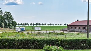Ländliche Landschaft mit einem Bauernhof, einem Wohnwagen und einem Baumfeld.