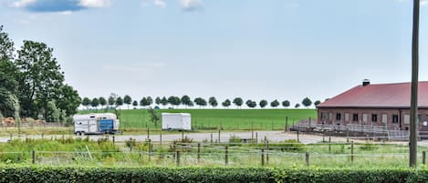 Een landelijk landschap met een schuur, een aanhangwagen en een boomgaard.