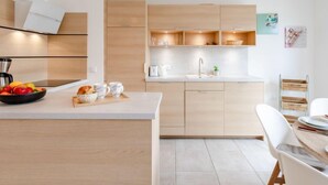 Eine moderne Küche mit Holzausstattung, einer weißen Arbeitsplatte und einem Essbereich mit weißem Tisch und Stühlen.