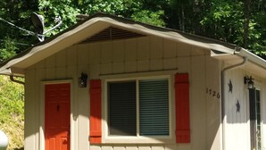 A small, single-story building with a beige exterior, red shutters, and a number '126' on the side.