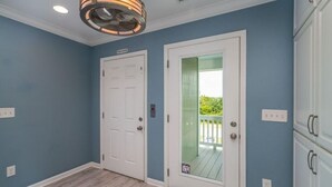 A room with a white door, a glass door leading to a balcony, and a ceiling fan. - Donovan's Out of the Blue  Great Value and Location! (Oak Island)
