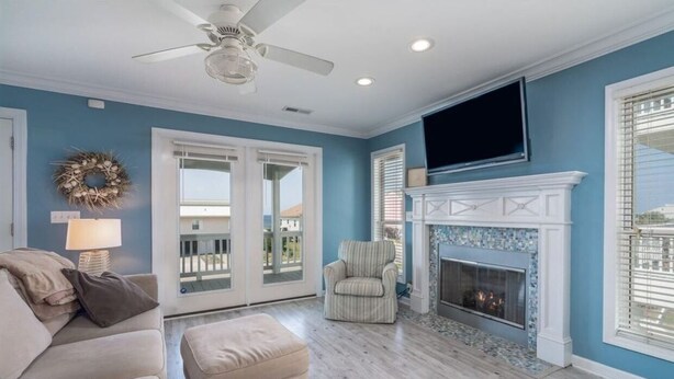 A living room with a fireplace, a ceiling fan, and a TV mounted above it. - Donovan's Out of the Blue  Great Value and Location! (Oak Island)