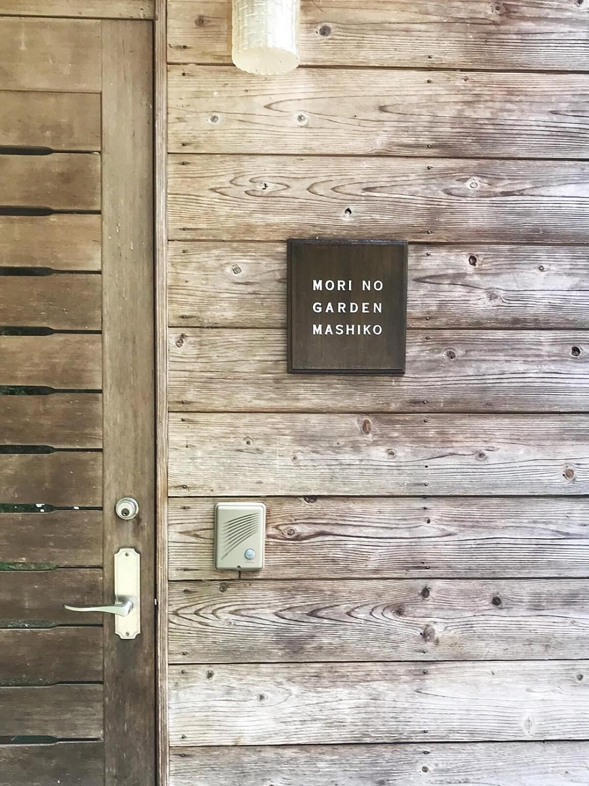A wooden door with a metal handle and a sign that reads "MORI NO GARDEN MASHIKO".