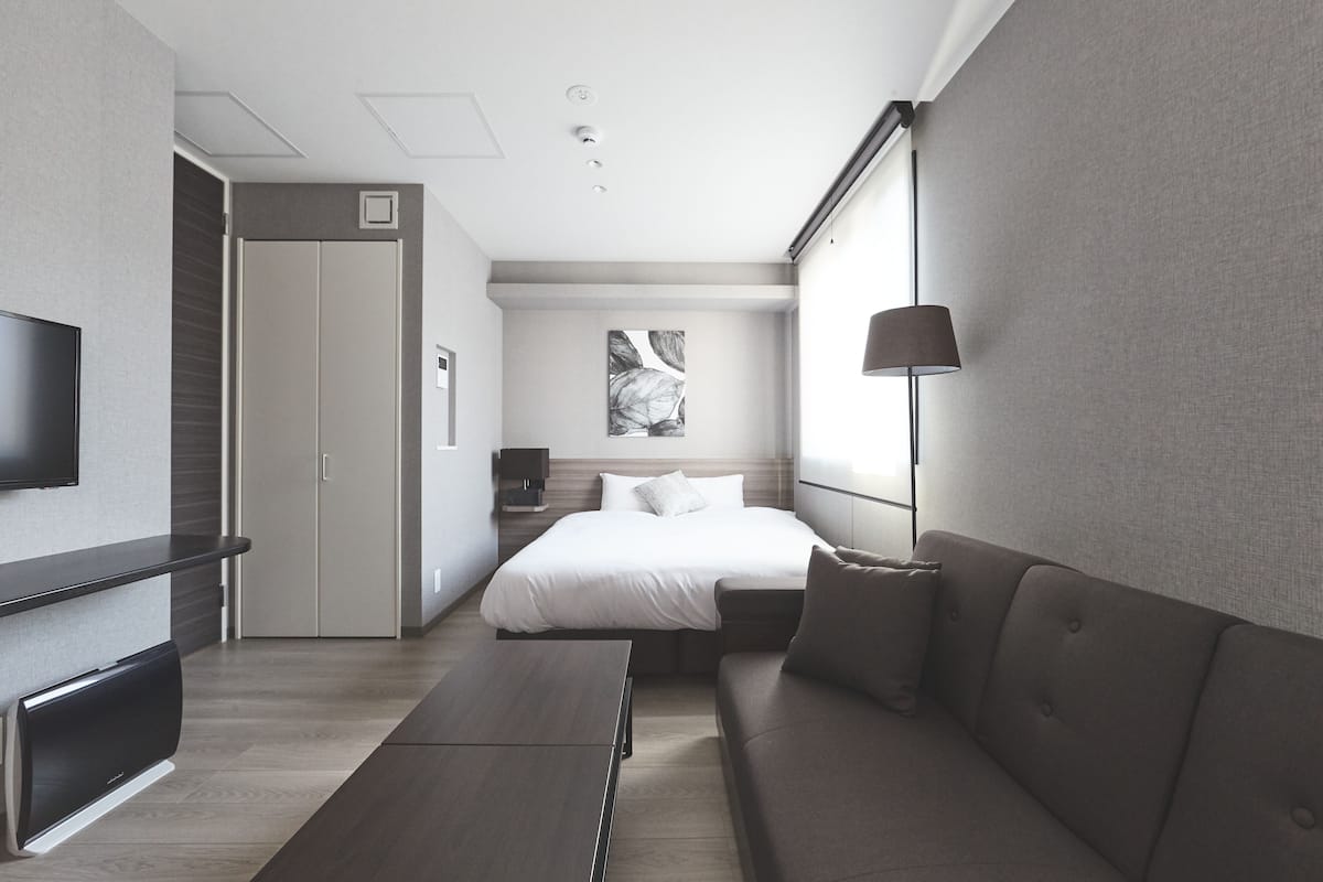 Une chambre d’hôtel moderne équipée d’un lit, d’un canapé, d’une télévision et d’une lampe.