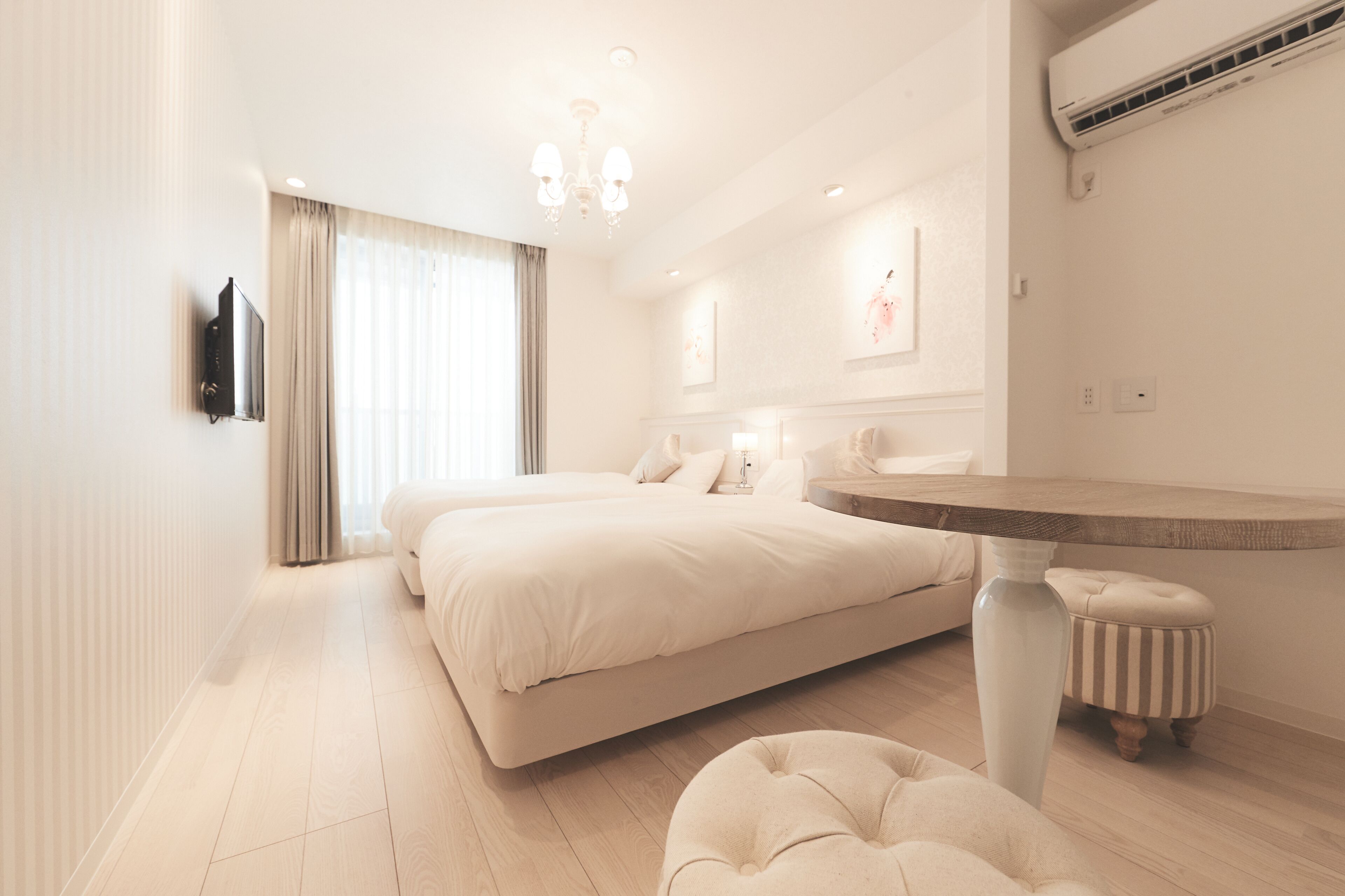 A modern bedroom with a large bed, a round table, and a TV mounted on the wall.
