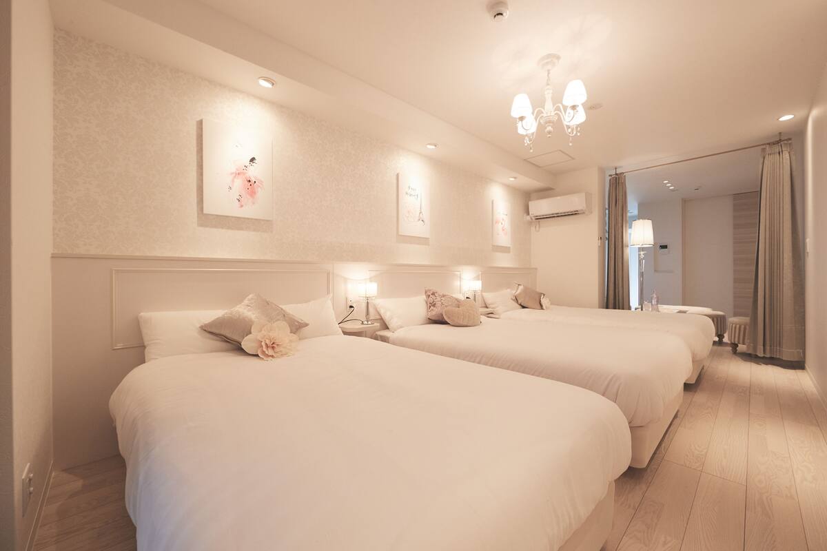 Une chambre d’hôtel avec deux lits, un lustre, des œuvres d’art murales et une vue sur l’extérieur.