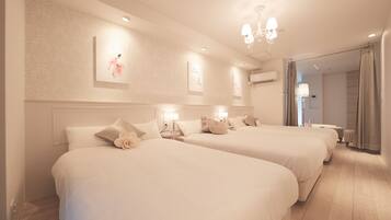 A hotel room with two beds, a chandelier, wall art, and a view of the outside.