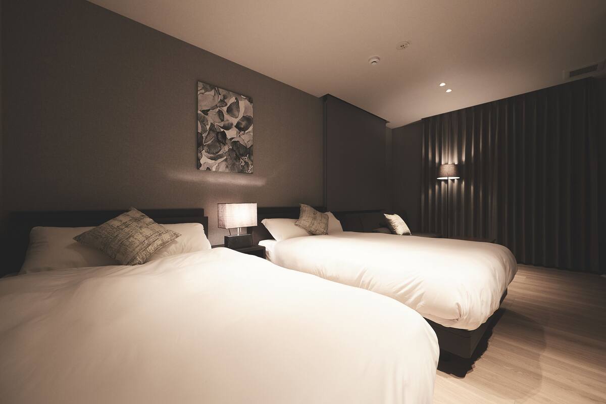 Une chambre d’hôtel avec deux lits, une table de chevet avec une lampe et une œuvre d’art accrochée au mur.