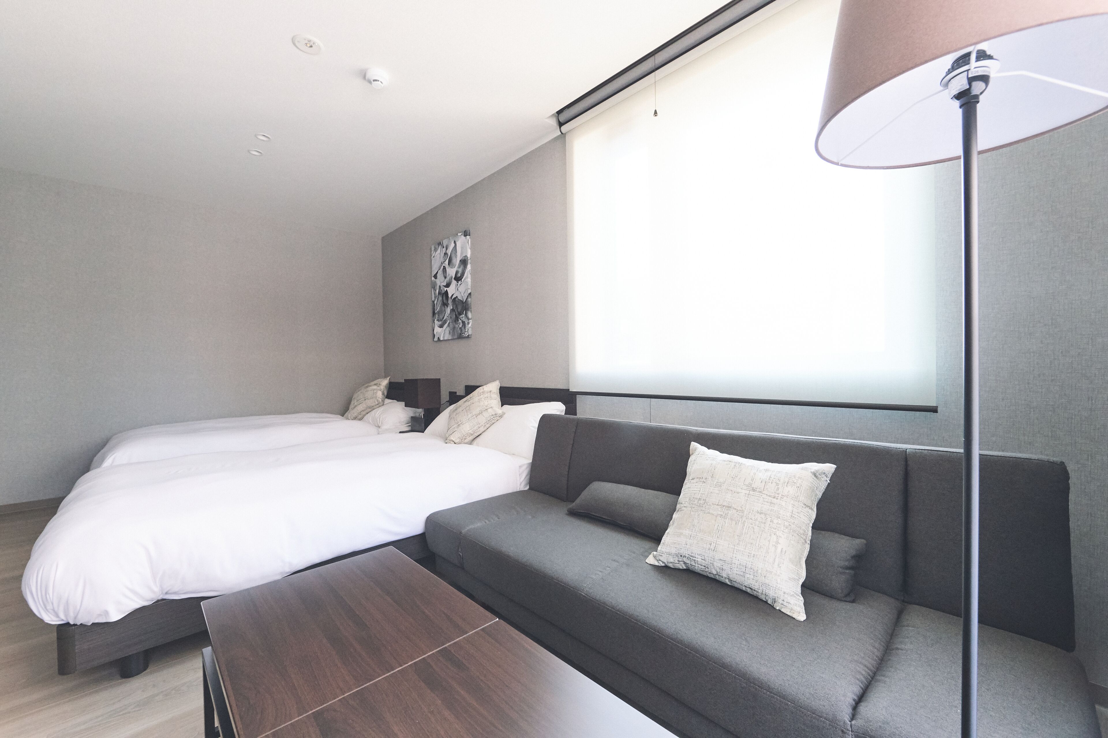 Una habitación de hotel moderna con una cama, un sofá y una lámpara de pie.
