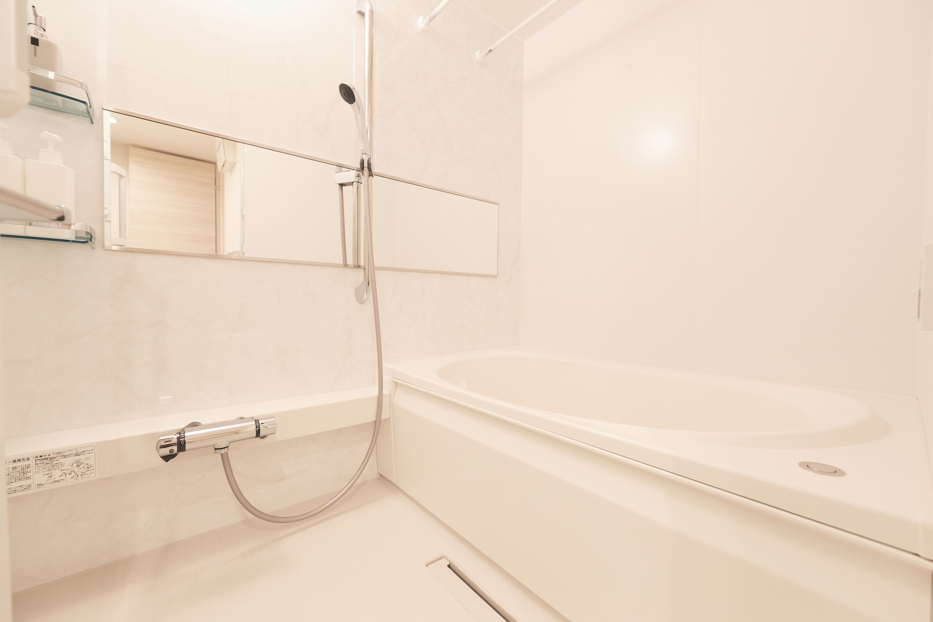 A modern bathroom with a bathtub, a shower, and a glass shelf with toiletries.