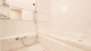 A modern bathroom with a bathtub, a shower, and a glass shelf with toiletries.