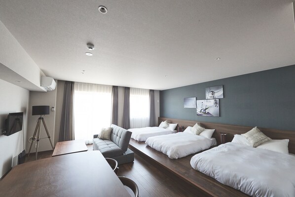 Habitación de hotel con dos camas, un escritorio, una silla, un televisor y un trípode.