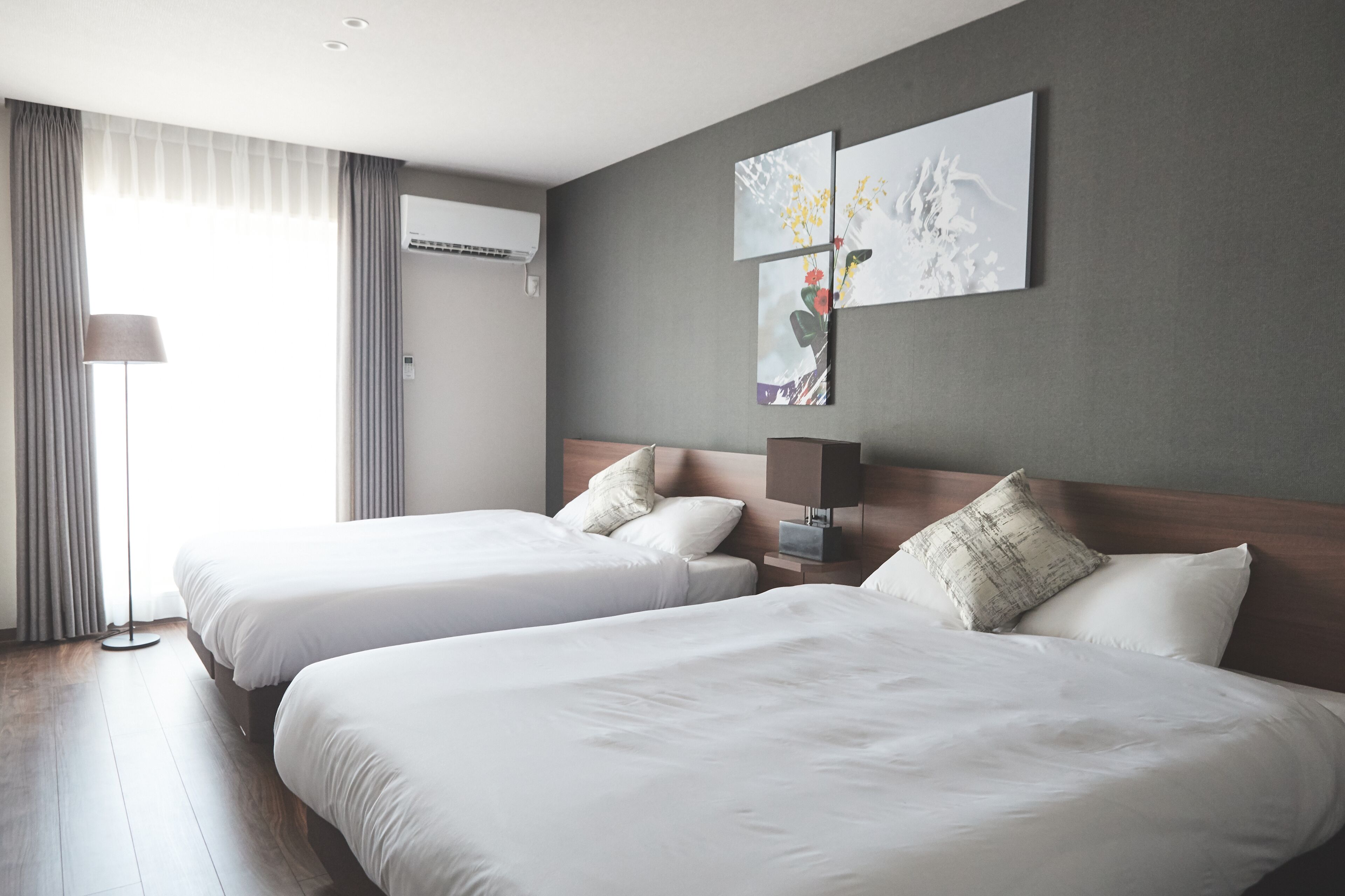 Une chambre d’hôtel avec deux lits, une lampe et des œuvres d’art accrochées au mur.