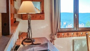 Una taula de fusta amb una làmpada, un mirall i una finestra que mostra vistes a les muntanyes.