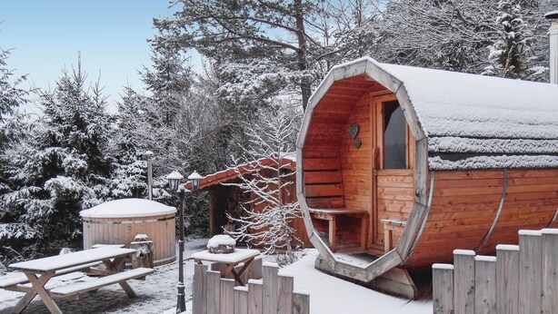 Una cabana de fusta amb façana coberta de neu, un balcó de fusta i una taula de picnic.