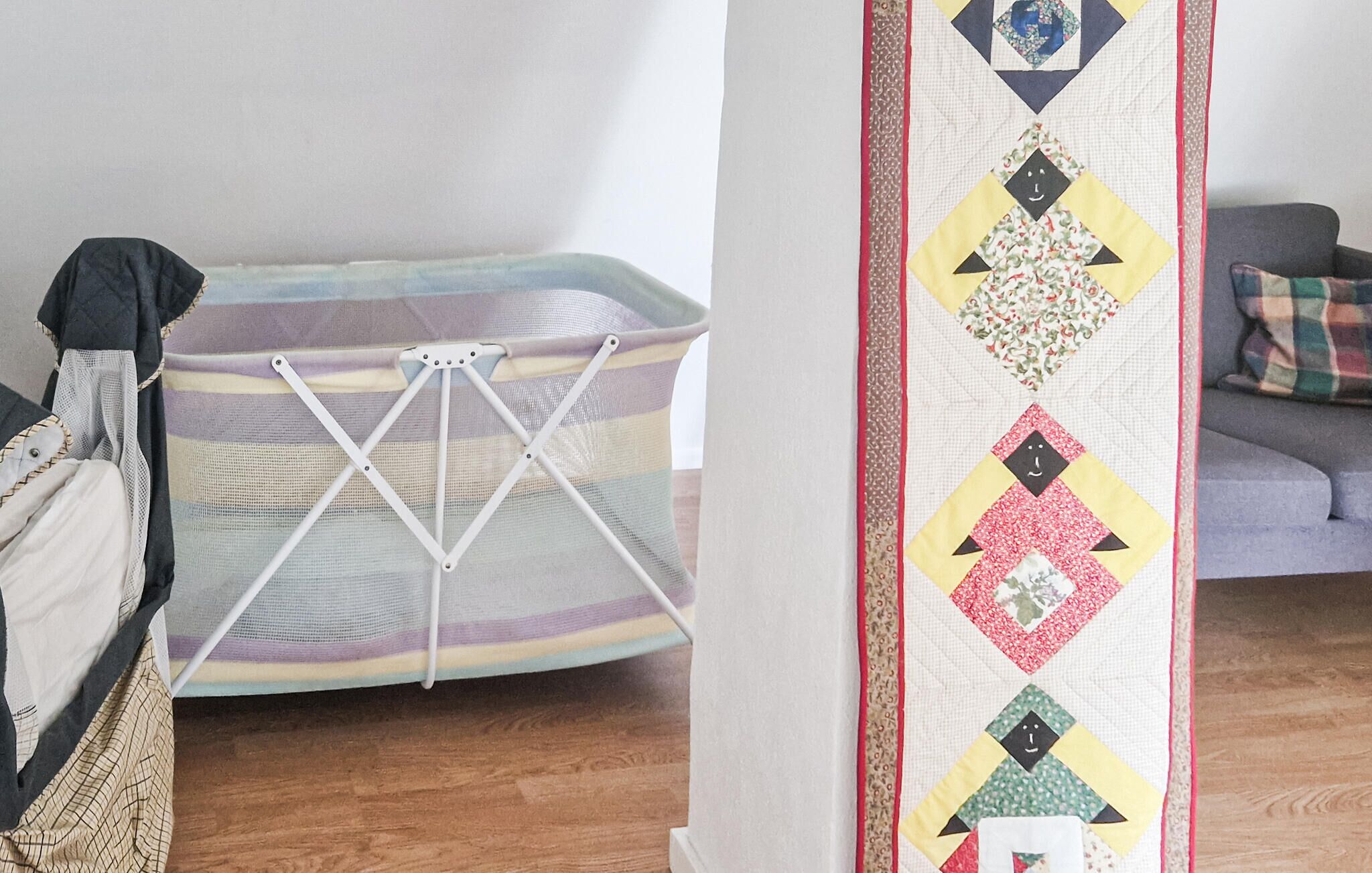 A room with a drying rack, a sofa, and a patterned wall.