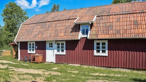 Ein rotes Holzhaus mit Ziegeldach, einer kleinen Veranda und einer Tür.