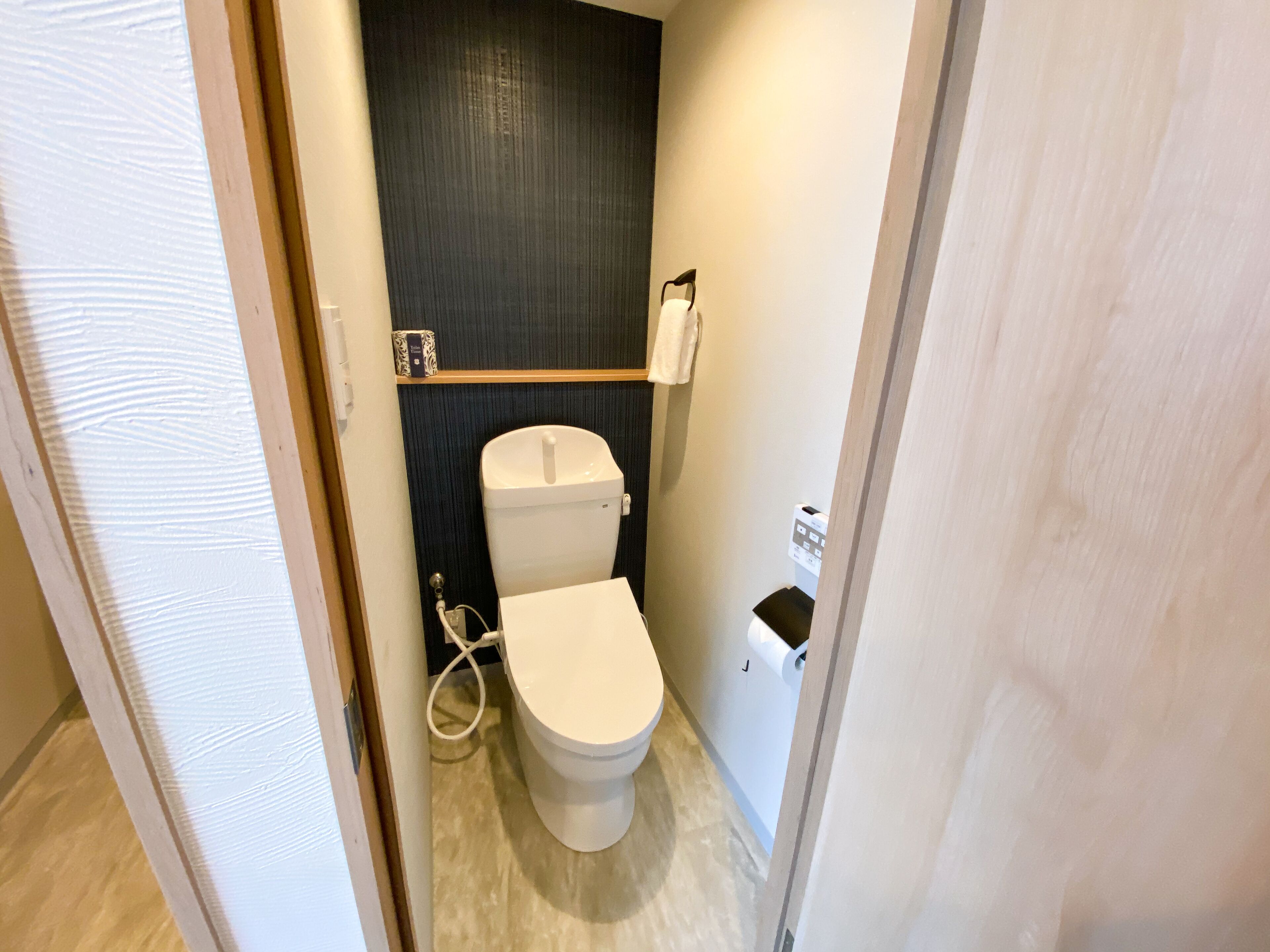 A small, modern bathroom with a toilet, a hand dryer, and a paper towel dispenser.