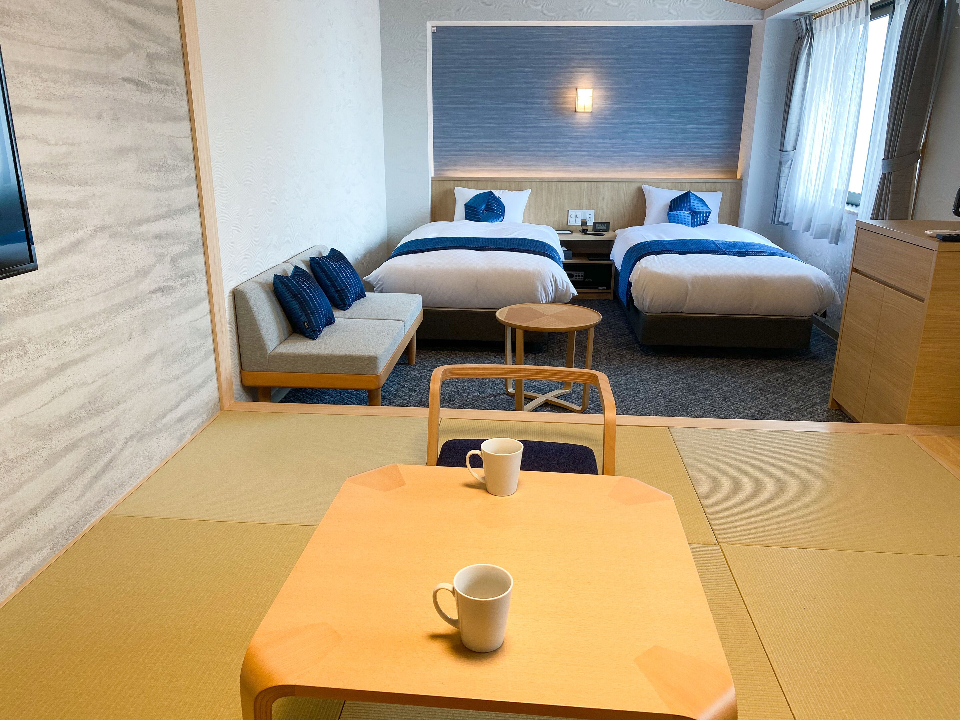 Une chambre d’hôtel avec deux lits, un canapé, une petite table, une chaise et un téléviseur.