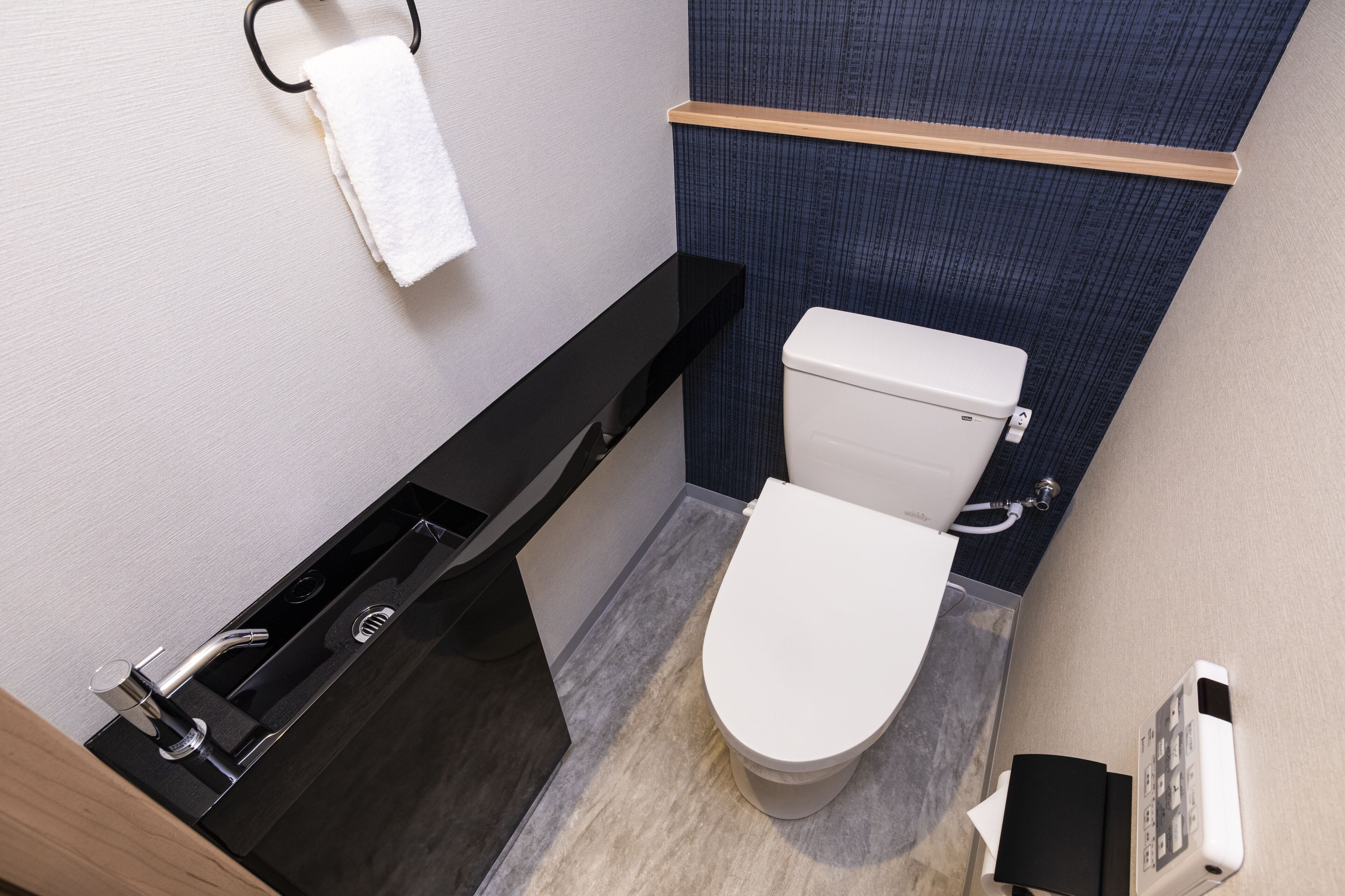 Un baño moderno con tocador negro, inodoro blanco y un perchero para toallas.