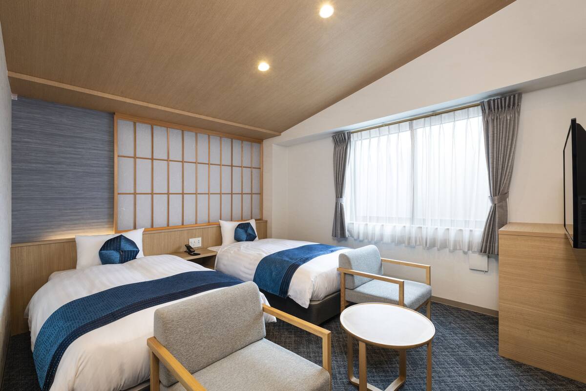 A hotel room with two beds, a small table, and a TV.