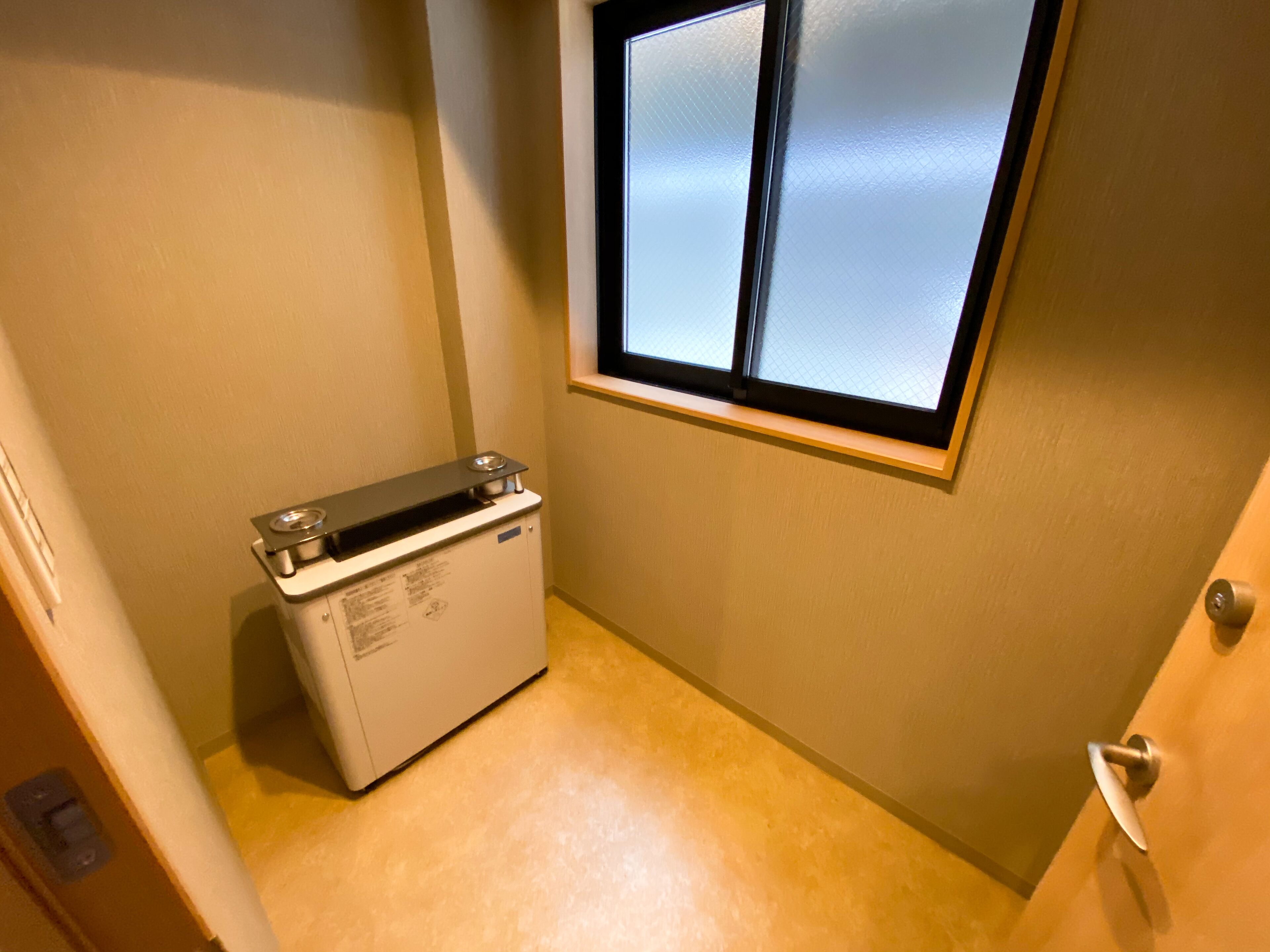 Ein kleiner Waschraum mit Waschmaschine, Fenster und Tür.