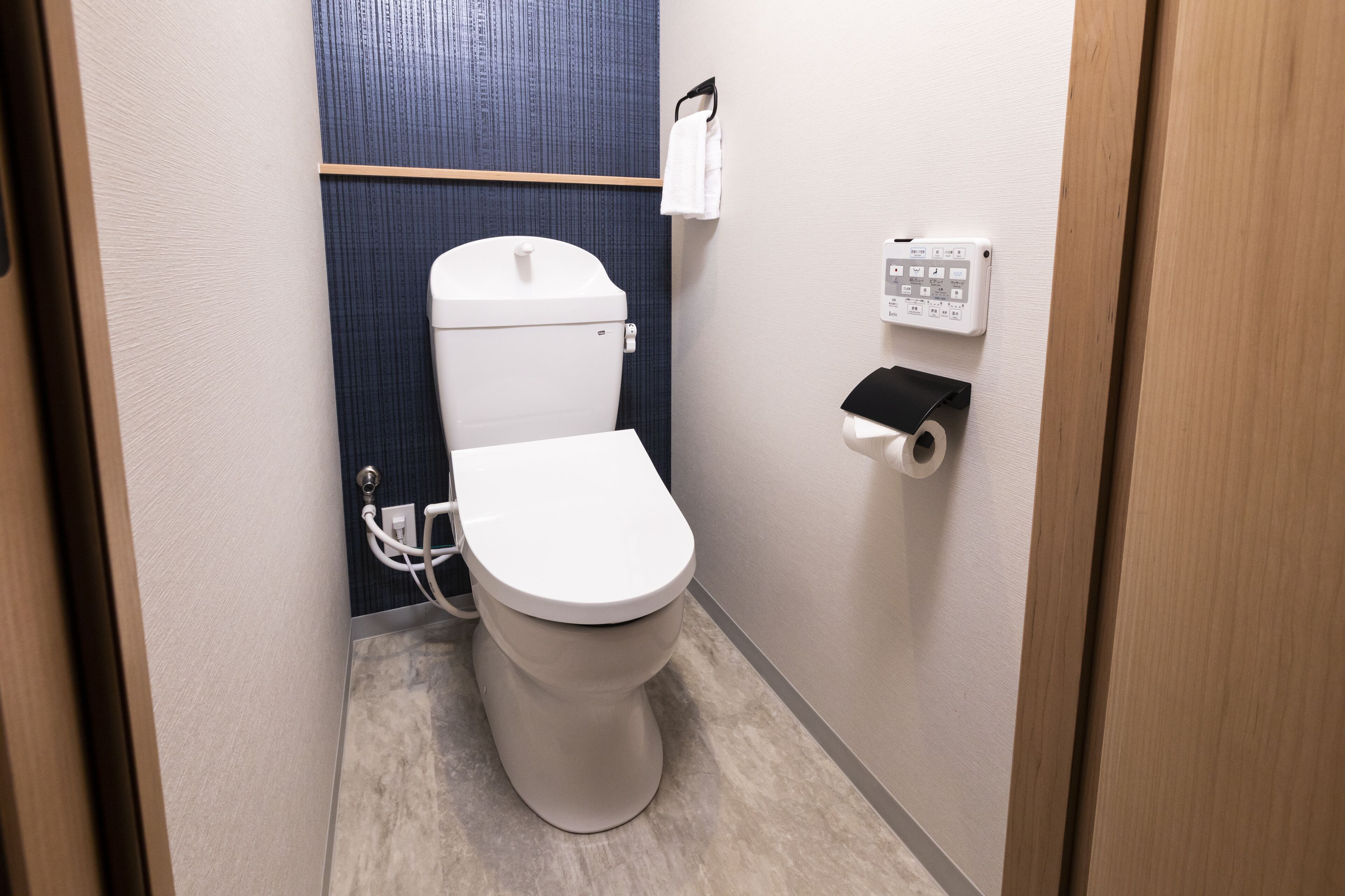 Une petite salle de bain équipée de toilettes, d’un sèche-mains et d’un distributeur de serviettes en papier.