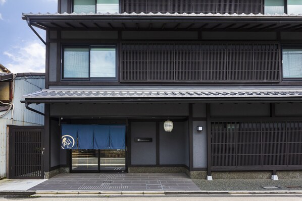 A modern building with a traditional entrance, a signboard, and a tiled roof. - Rinn Niomon (Kyoto)