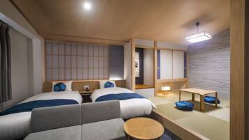 Habitación de hotel con dos camas, un sofá, una mesita y un separador de estilo japonés tradicional.