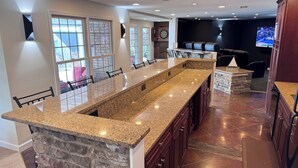 A modern kitchen with granite countertops, a stone accent wall, and a dining area with leather seating. - The Fun Spot 3 - Serene Home with Beautiful Lake & Mtn Views to Relax and Enjoy! (Huddleston)