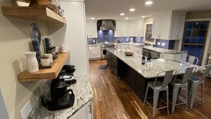 A modern kitchen with white cabinets, a granite countertop, and a central island with bar stools. - The Fun Spot 3 - Serene Home with Beautiful Lake & Mtn Views to Relax and Enjoy! (Huddleston)