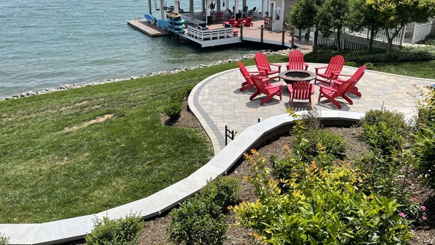 A lakeside patio with red Adirondack chairs, a fire pit, and a covered seating area with a view of the water. - The Fun Spot 3 - Serene Home with Beautiful Lake & Mtn Views to Relax and Enjoy! (Huddleston)