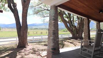 Relax in a serene outdoor seating area surrounded by a white fence, offering a peaceful view of the surrounding countryside.