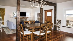 A dining area with a wooden table and chairs, a television, and a view of the outdoors.