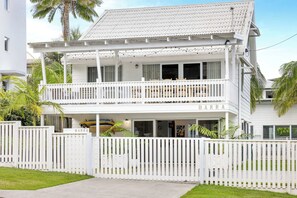 A two-story white house with a balcony, a gated entrance, and a sign that reads 'BARRA'.