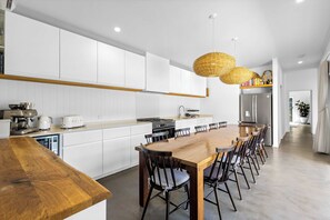 A modern kitchen with white cabinetry, a wooden dining table, and a built-in oven.