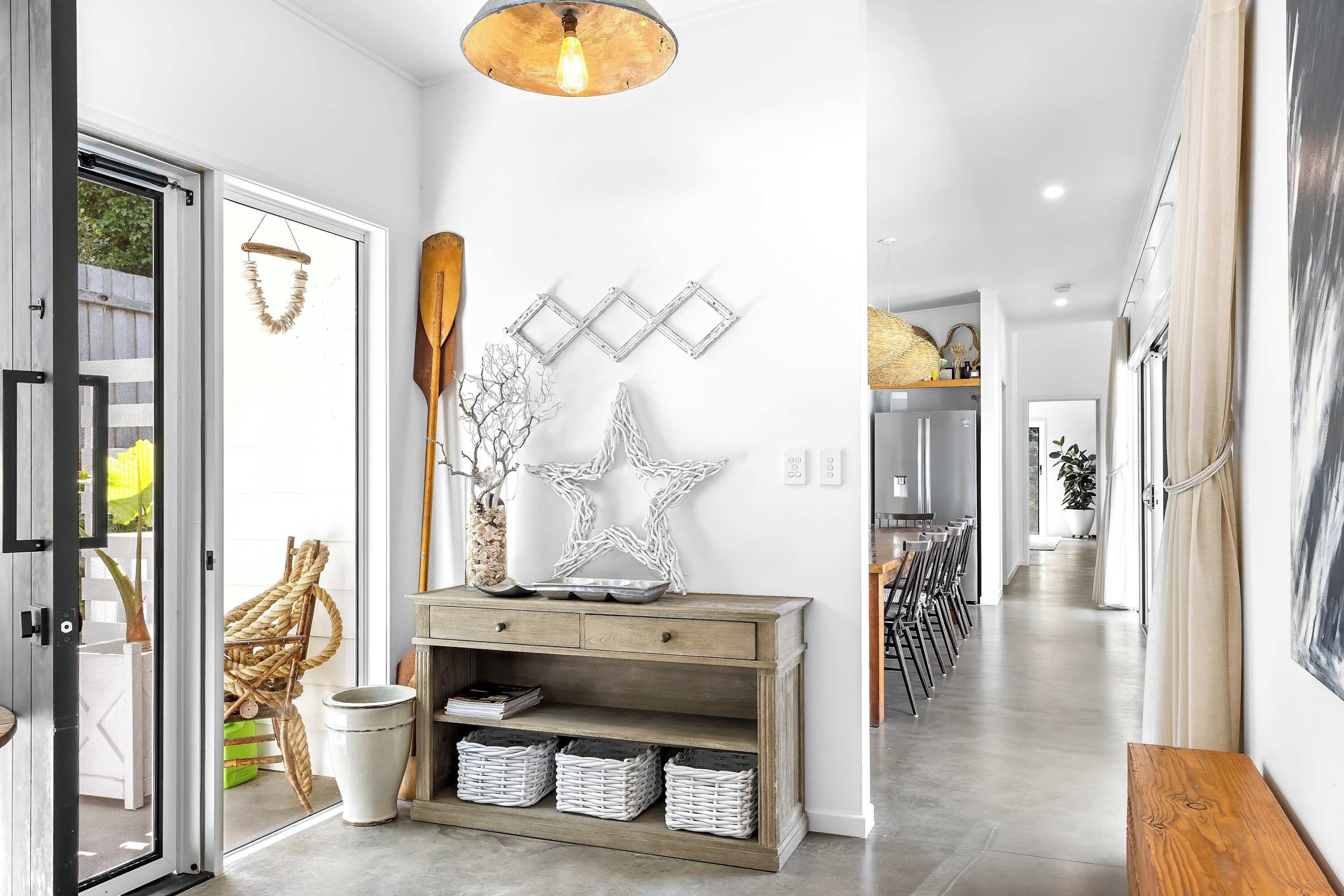 A modern hallway with a wooden console table, wicker baskets, and a star-shaped wall decoration.