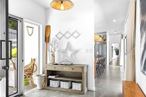A modern hallway with a wooden console table, wicker baskets, and a star-shaped wall decoration.