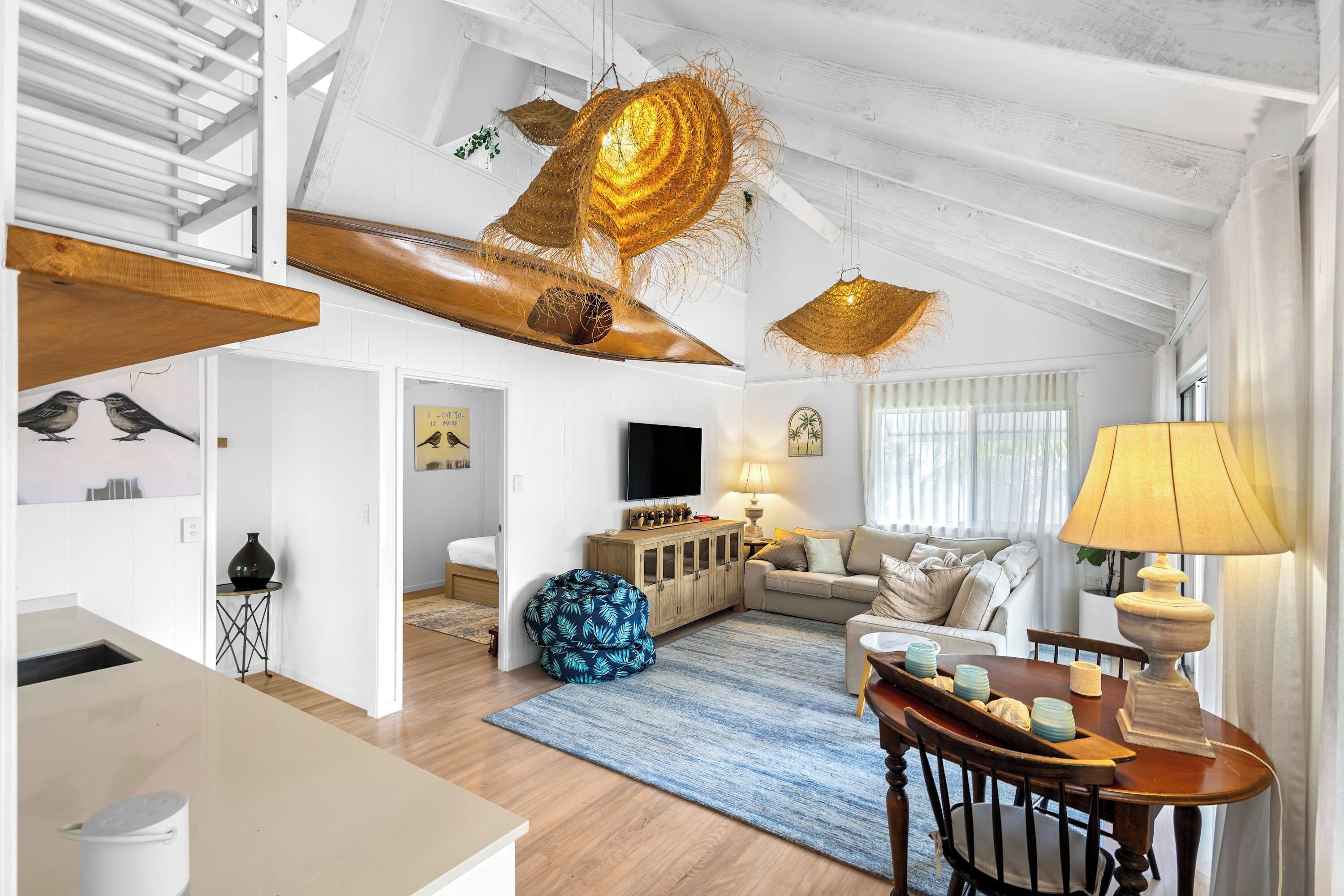 A spacious living area with a high ceiling, a sofa set, a coffee table, and a television.