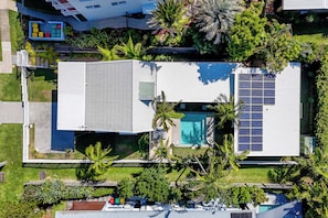 A modern house with a swimming pool, solar panels, and a well-maintained garden.