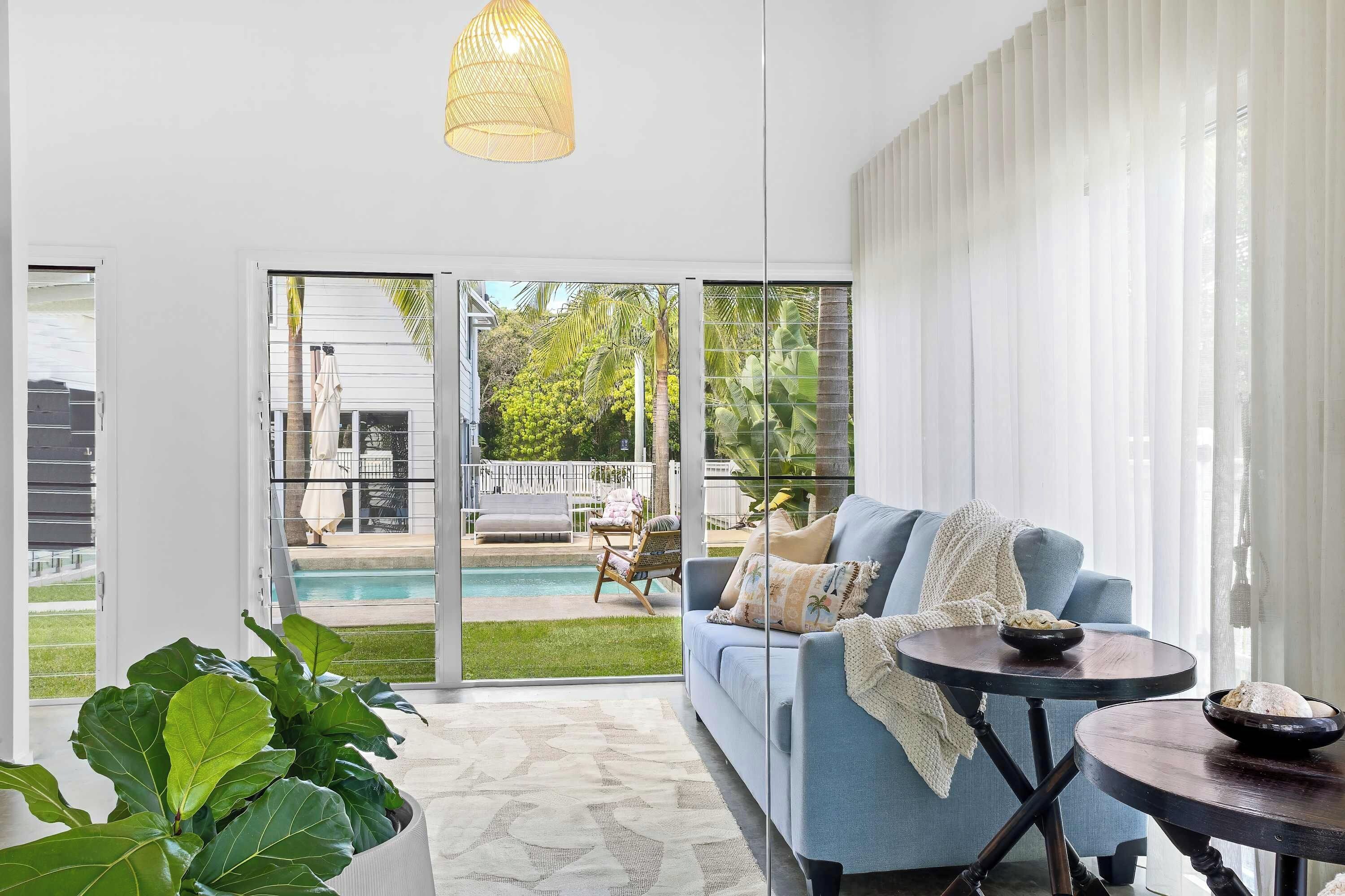 A modern living room with a blue sofa, a round table, and a view of a pool and outdoor furniture.