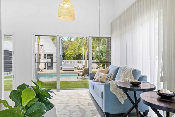 A modern living room with a blue sofa, a round table, and a view of a pool and outdoor furniture.