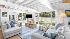 A spacious living room with a large TV, comfortable seating, and a view of the outdoors. - Barra Luxe Beach House 4BR Yaroomba (Point Arkwright)