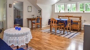 Un comedor con una mesa y sillas de madera, un mantel de encaje y vistas al exterior a través de amplios ventanales.